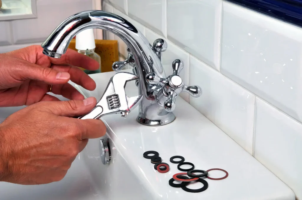 Plumber performing maintenance on a bathroom faucet in Seaside