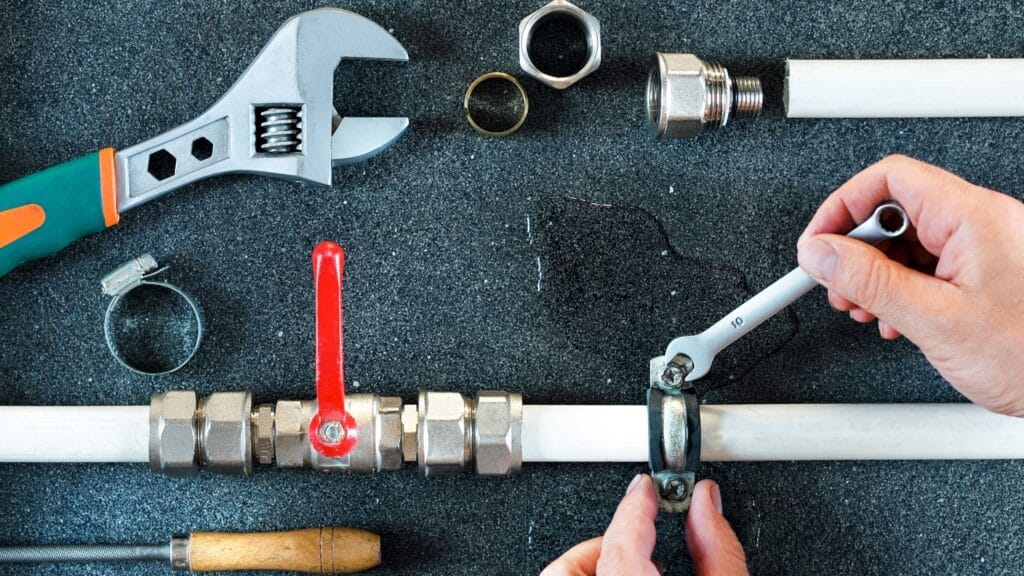 Plumber repairing a pipe valve with an adjustable wrench in Seaside