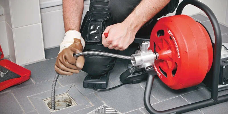 Plumber using a drain-cleaning machine in Seaside