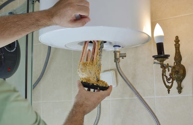 Technician removing mineral buildup from a water heater in Seaside