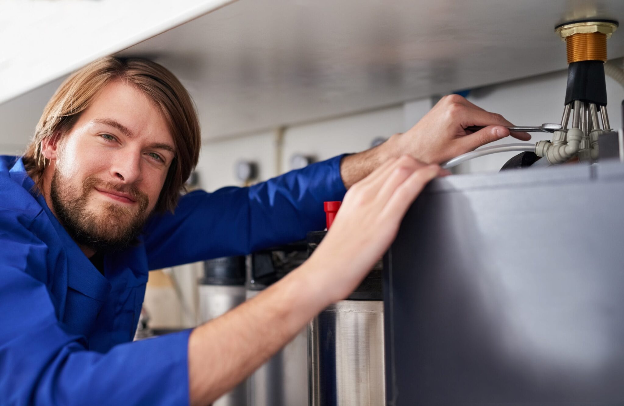 Technician servicing a residential water heater tank in Seaside