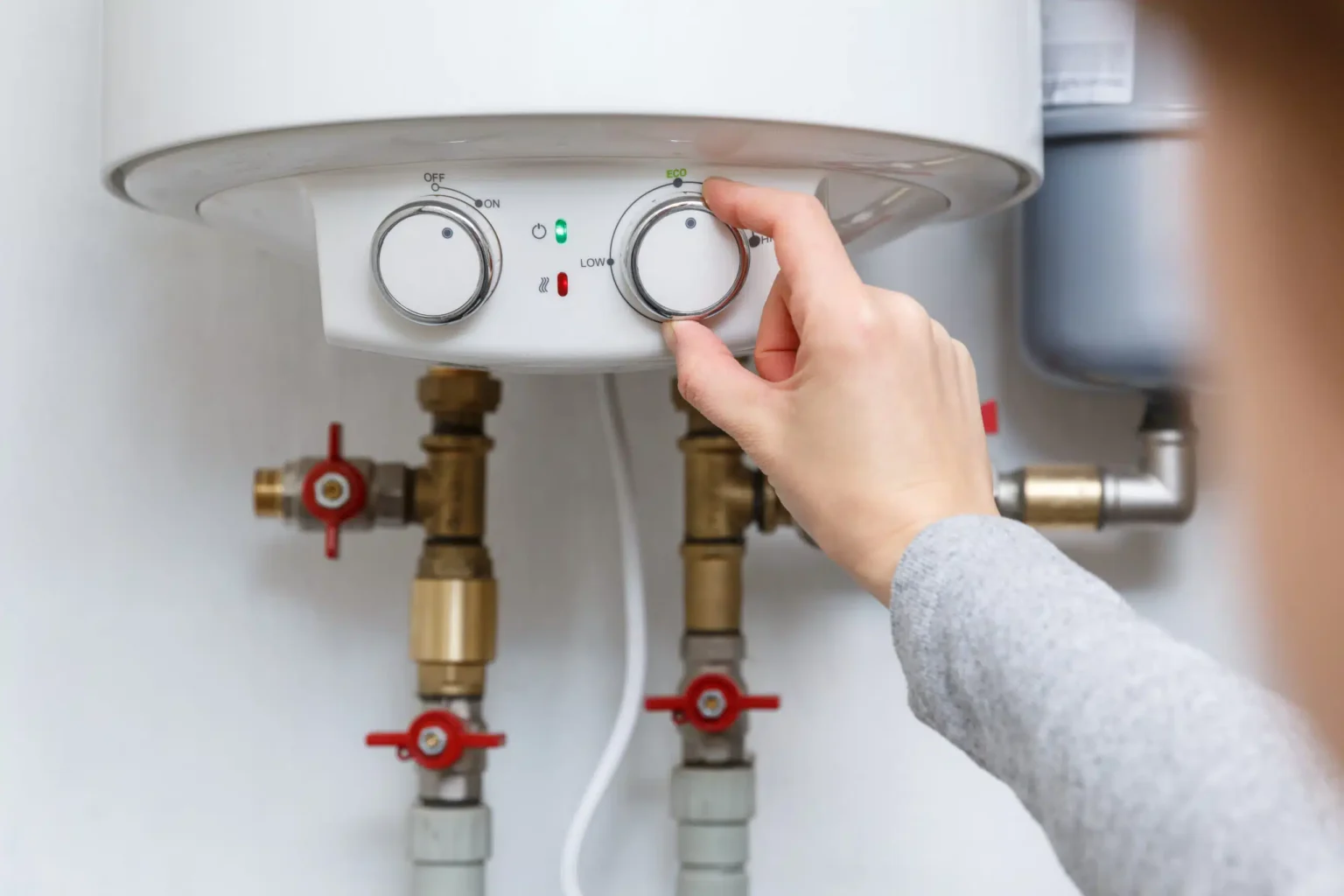 Homeowner adjusting the temperature controls on a water heater in Seaside